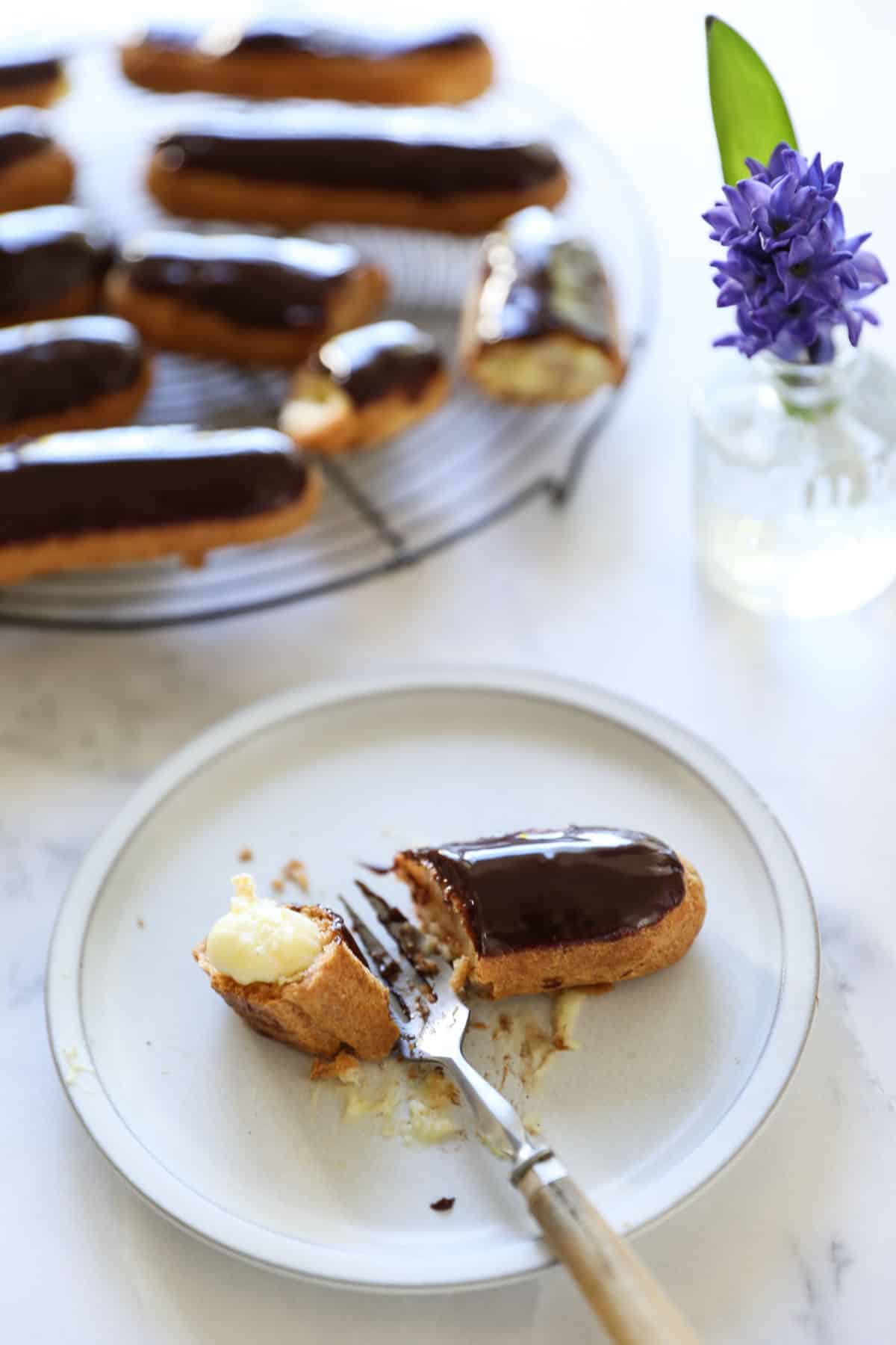 an eclair with a chocolate glaze and fork taking a bite