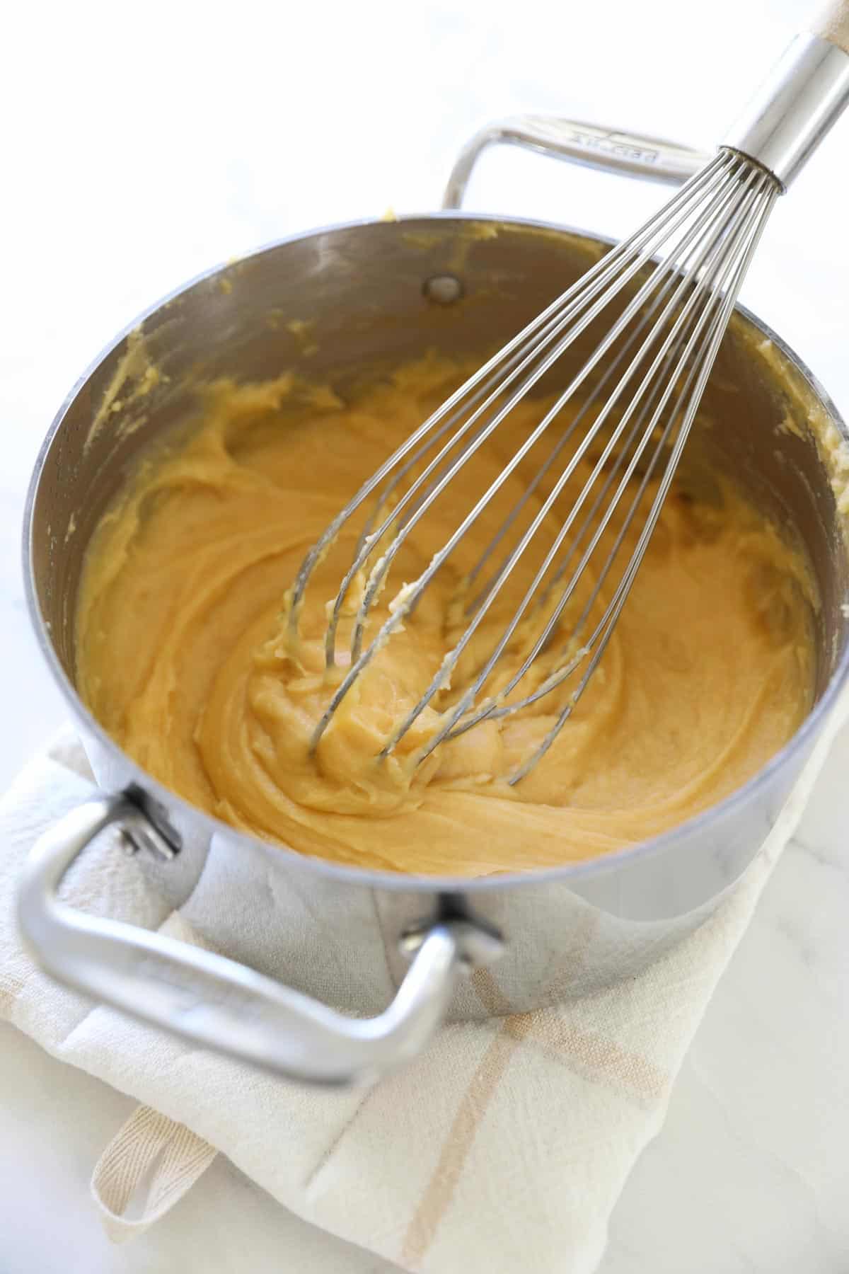 a pot with choux pastry batter and a whisk