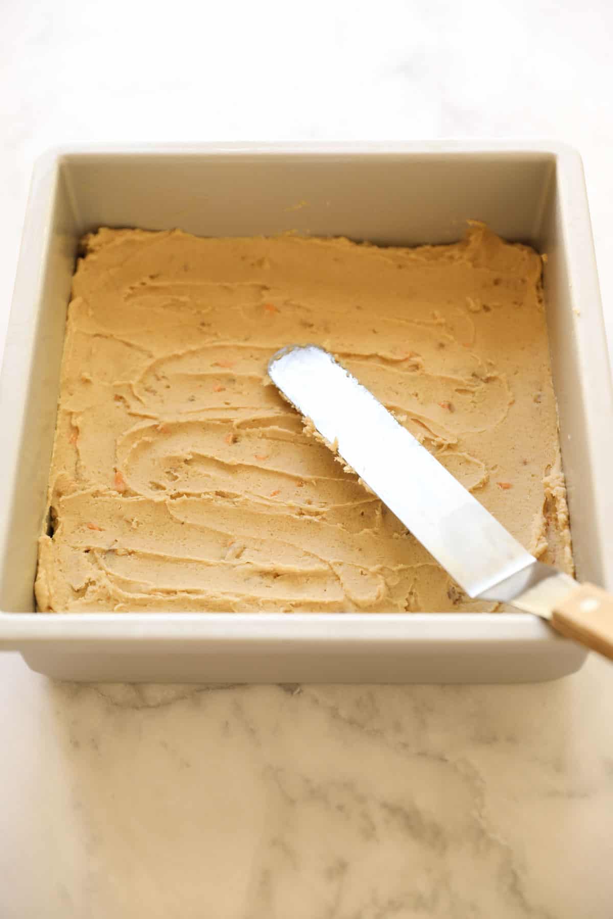 a pan of brownie batter smoothed out with an offset spatula