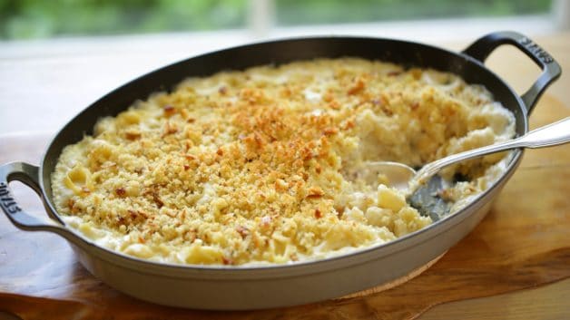 Large gratin pan full of baked mac and cheese with serving spoon