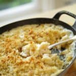 Large gratin pan full of baked mac and cheese with serving spoon