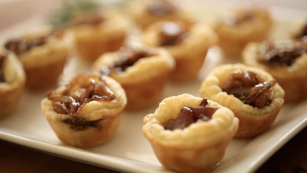 a collection of mini tarts made with puff pastry on a white platter