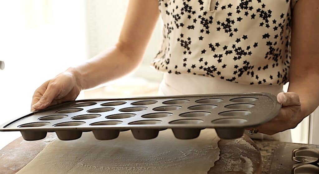 a person holding a mini muffin tin