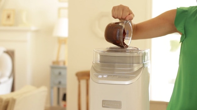 Melted chocolate being poured from a Pyrex pitcher into a running Ice Cream Machine