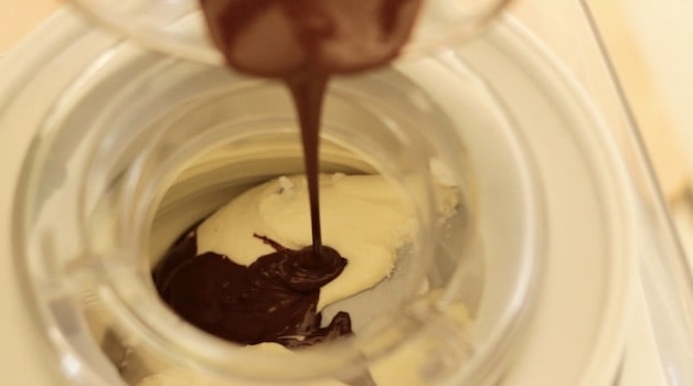 Close up of melted chocolate being added to churning ice cream in an ice cream machine