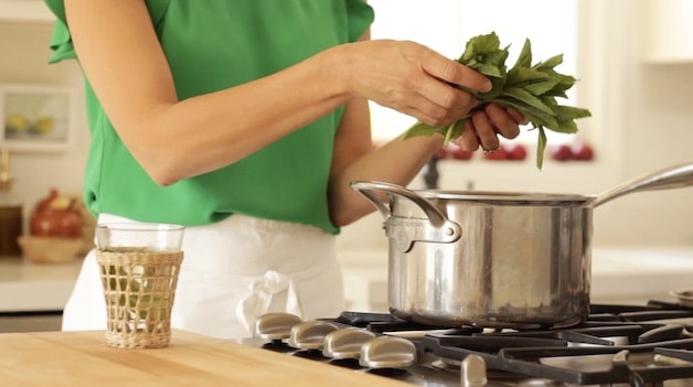 Adding fresh mint stems to a saucepot