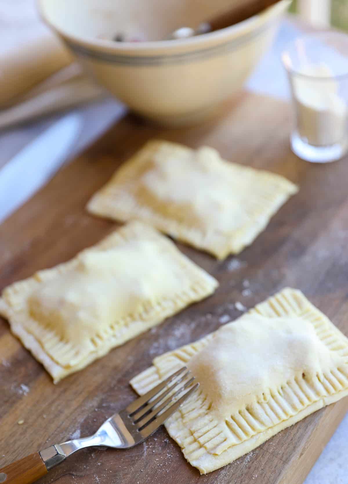 a fork sealing a pastry together on a cutting board