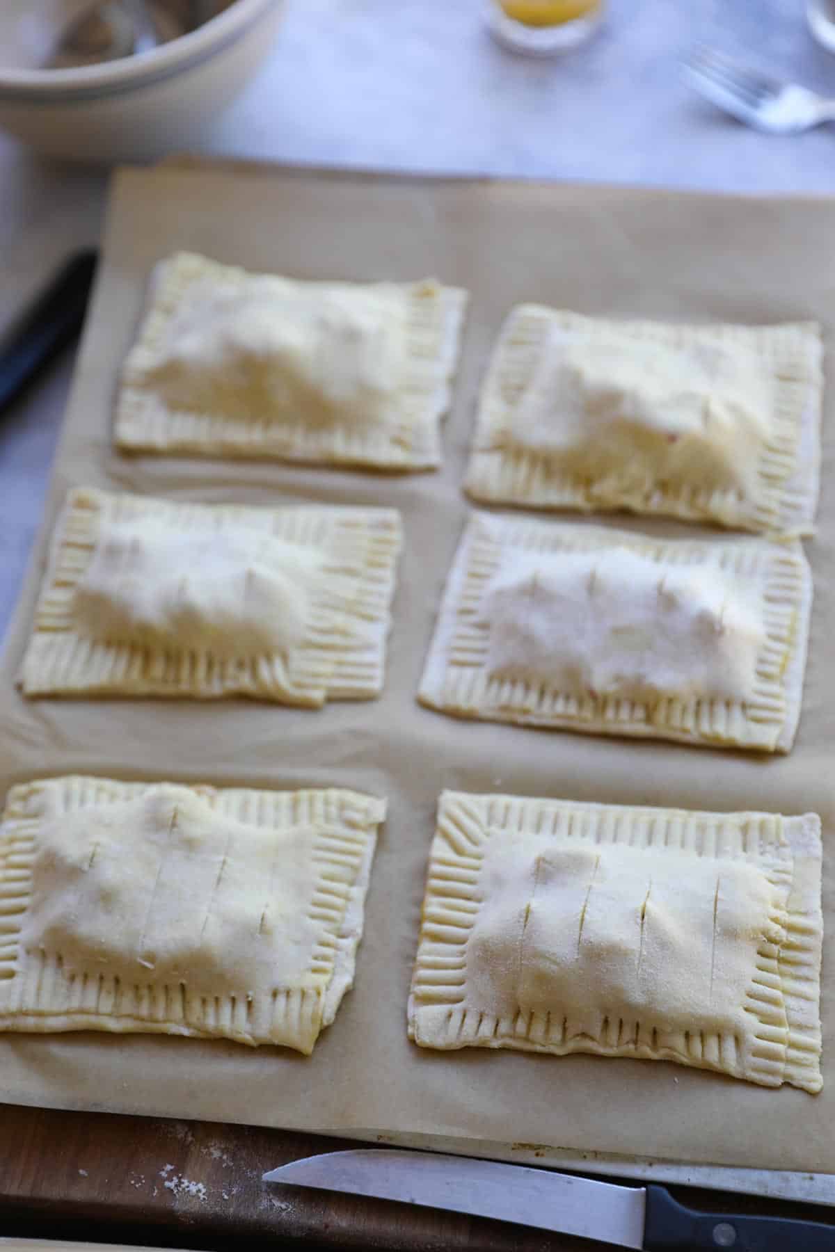 apple pastrries filled on a sheet pan ready for the oven