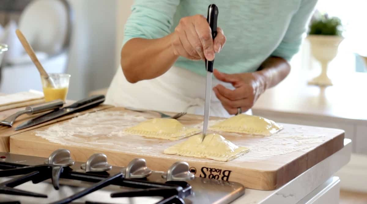 adding slits to a pastry on a board