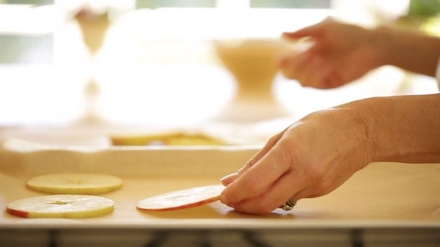 Placing apple slices on a baking sheet lined with parchment paper