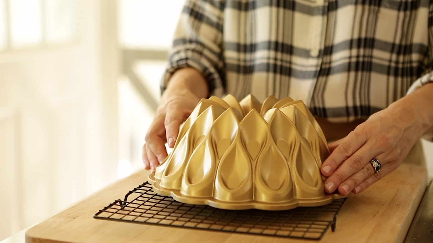 A woman with hands on a gold bundt pan