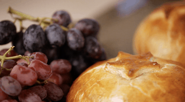 a close up of Baked brie in puff pastry with grapes in the background