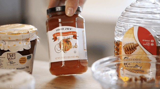 A person tilting a jar of Apricot Jam