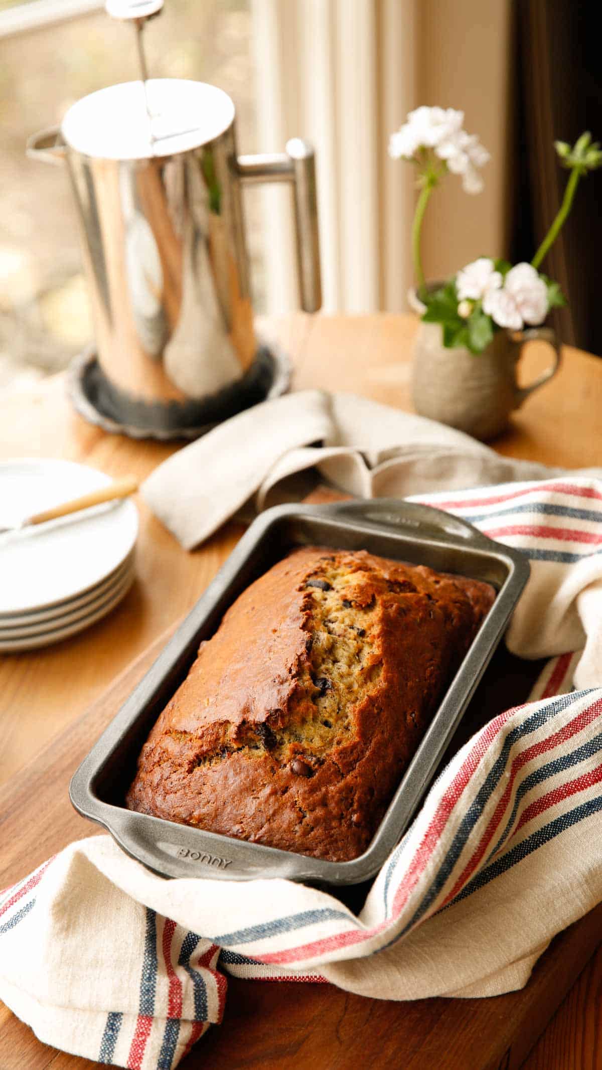 A table set with a loaf of banana bread coffee pot and plates