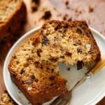 a slice of banana bread on a plate with a fork showing its moist texture