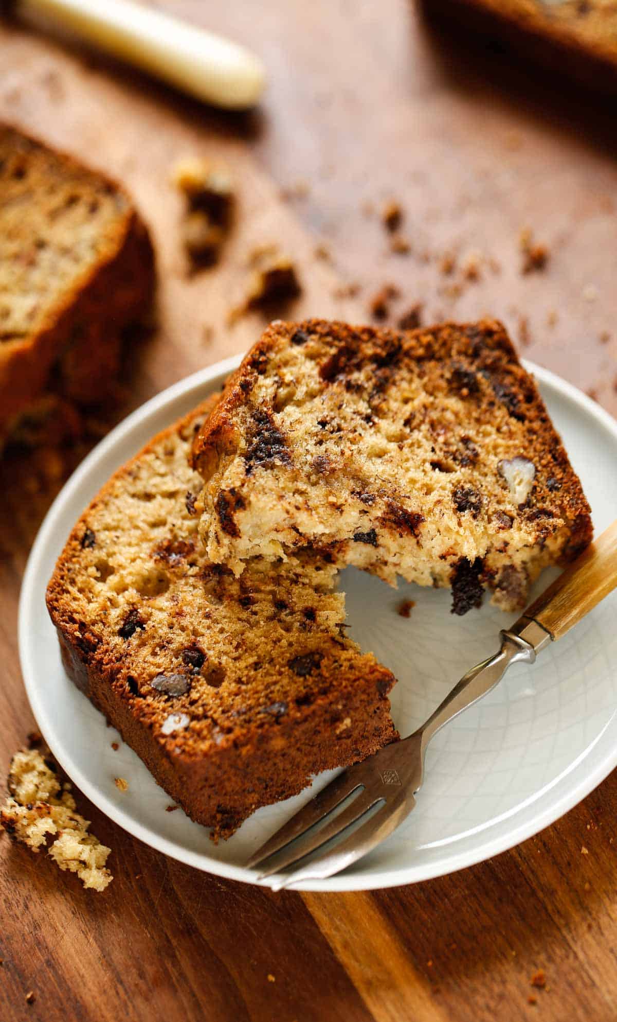 a slice of banana bread on a plate with a fork showing its moist texture