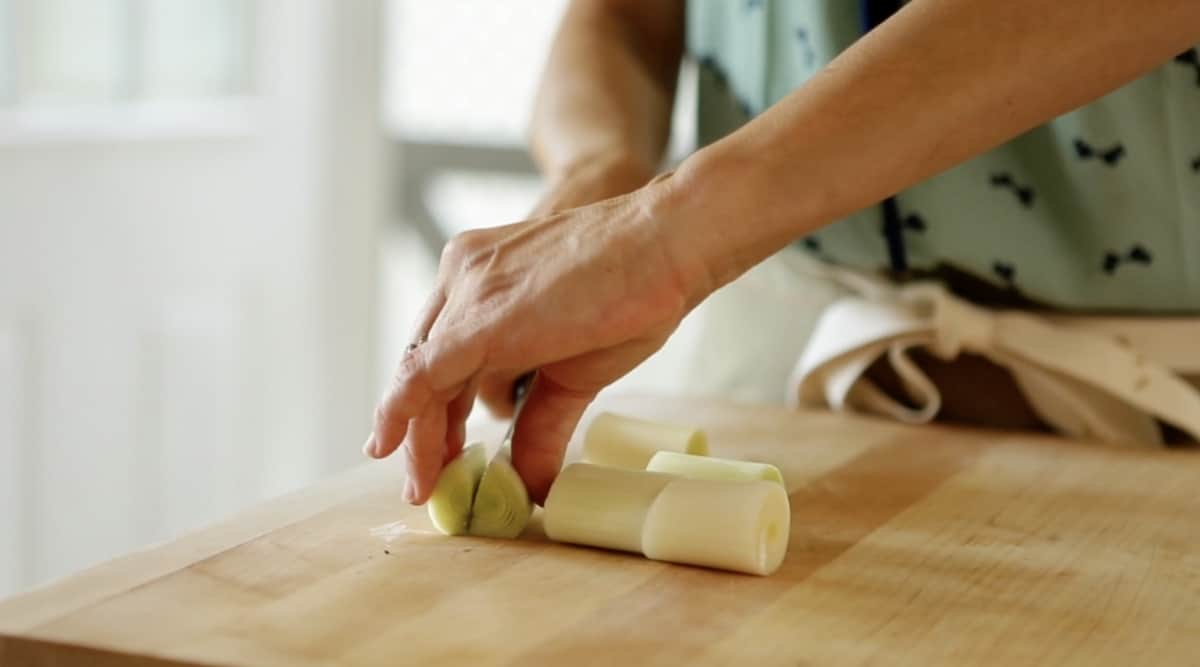 a person slicing leeks on a cutting board