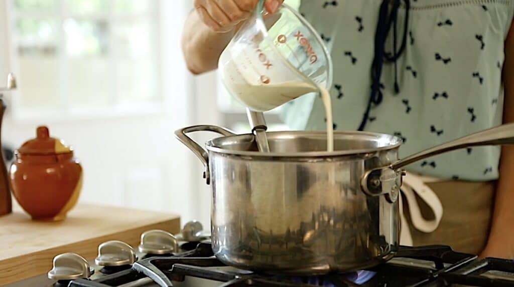 adding cream to a sauce pot