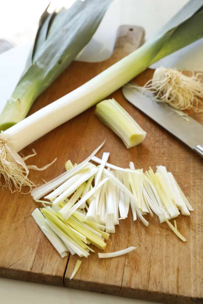 Sliced leeks cut into strips on a cutting board.