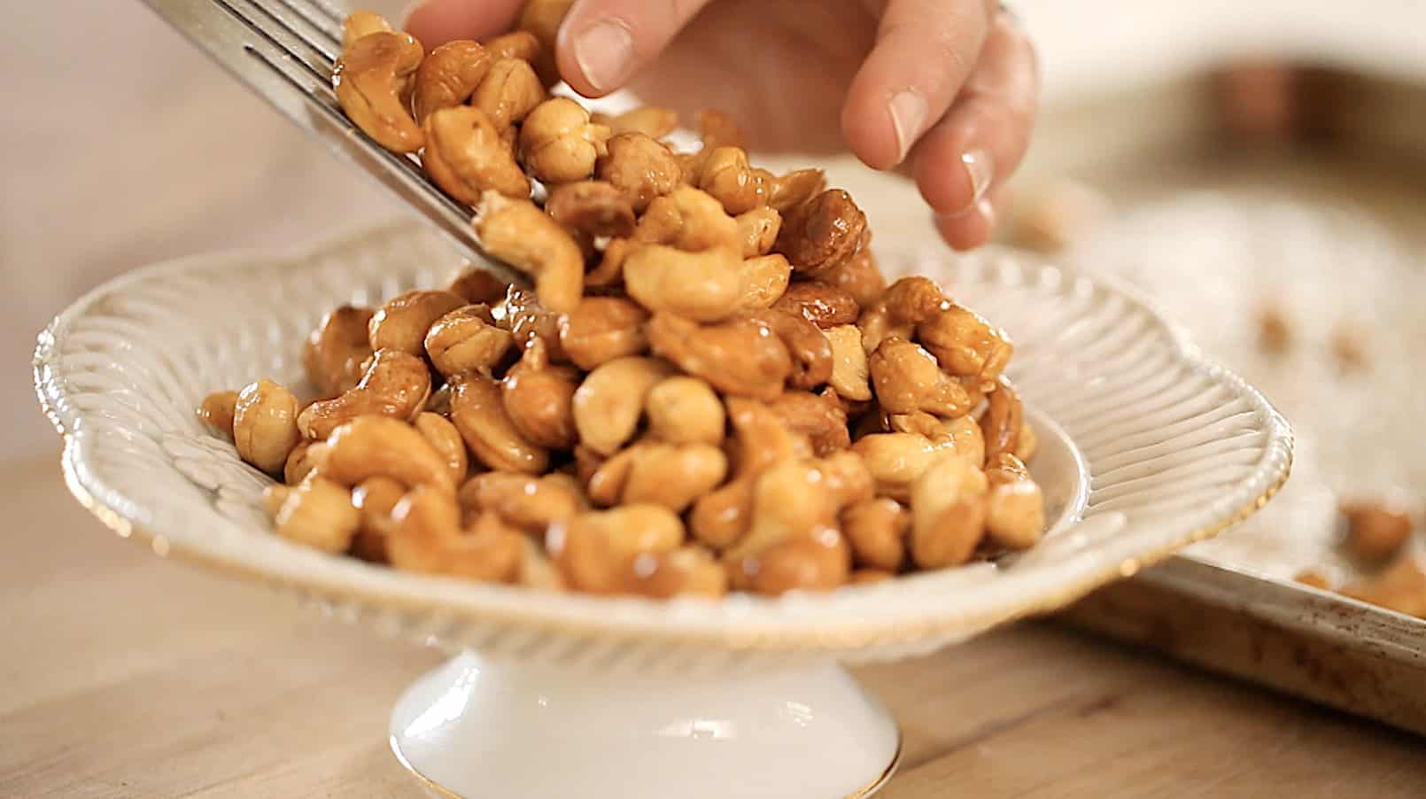 a person adding honey nuts to a bowl 