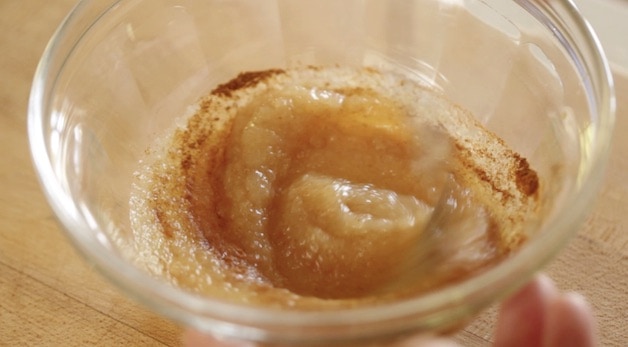 cinnamon swirled into apple sauce in a glass bowl