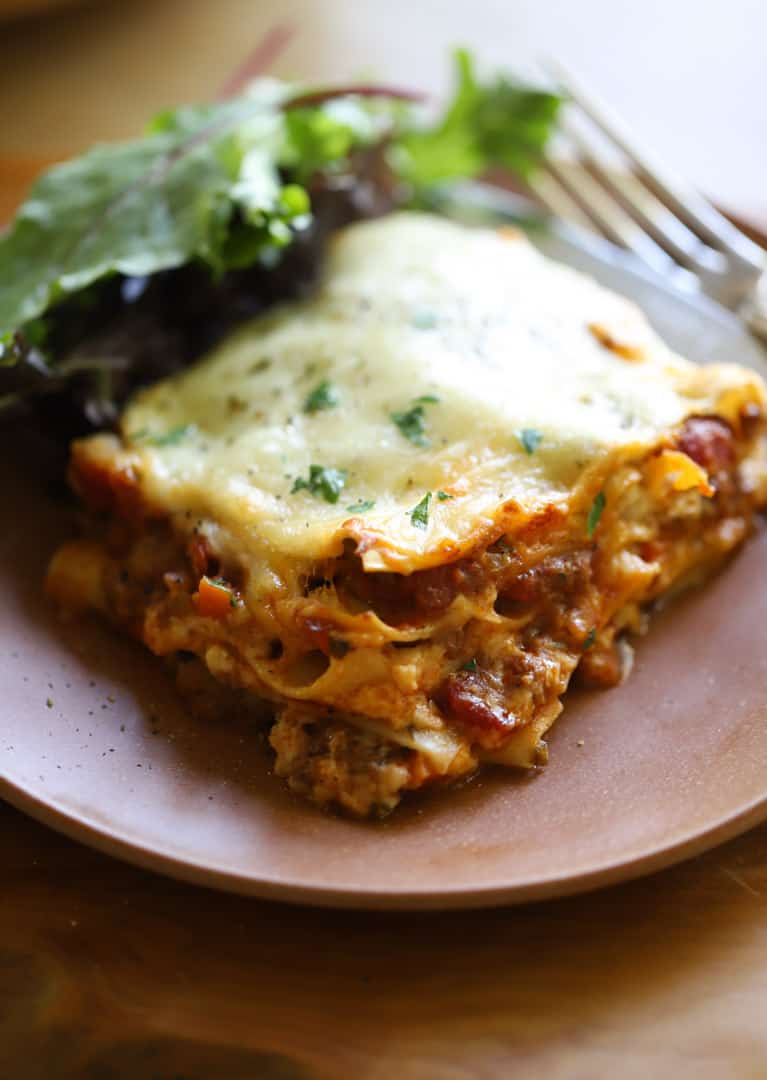 a slice of lasagna on a plate with a salad