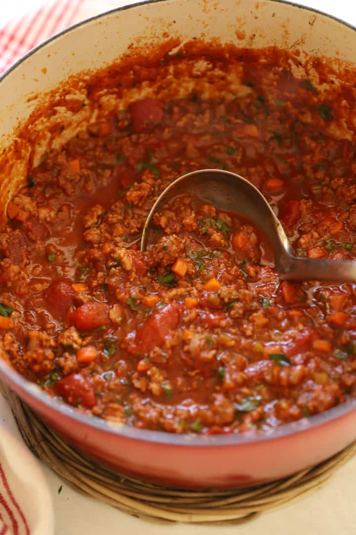a pot filled with Bolognese sauce and a ladle