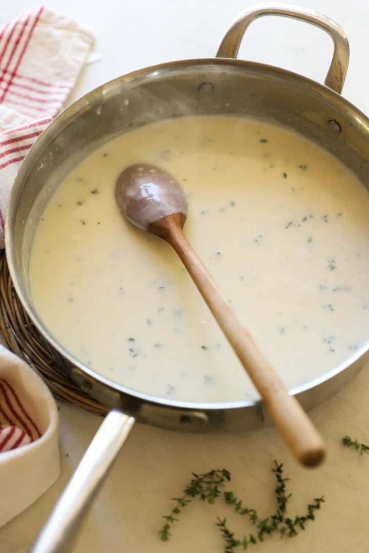Bechamel sauce in a skillet with a wooden spoon