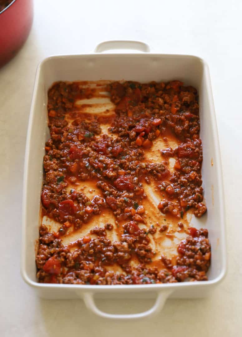 Bolognese sauce added to the bottom of a lasagna pan