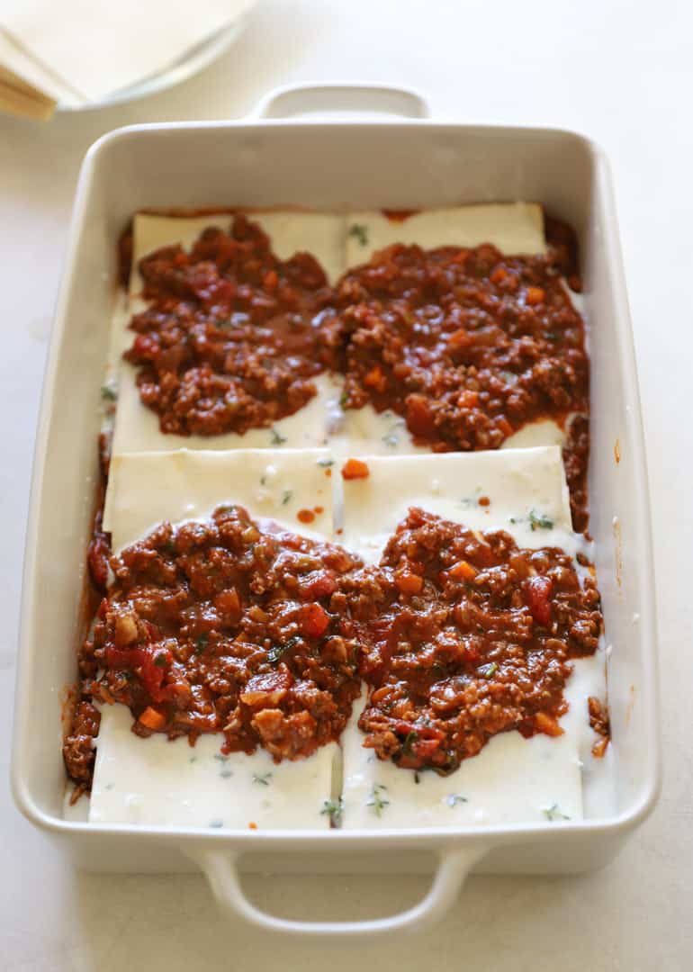 the first layer of a lasagna with noodles, bechamel sauce and meat sauce