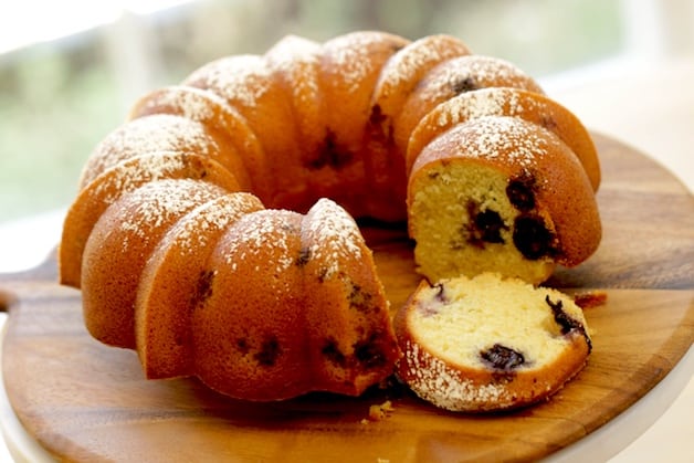 Lemon Blueberry Bundt Cake with a slice resting by its side on a cutting board