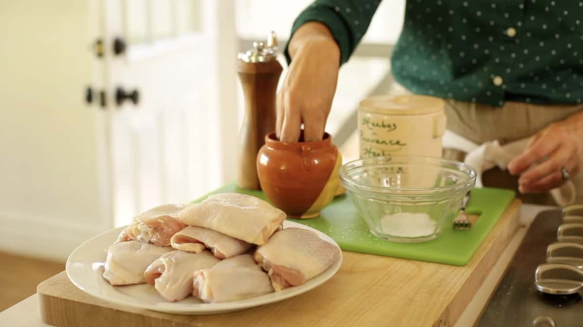 seasoning chicken with salt, pepper and herbs de Provence