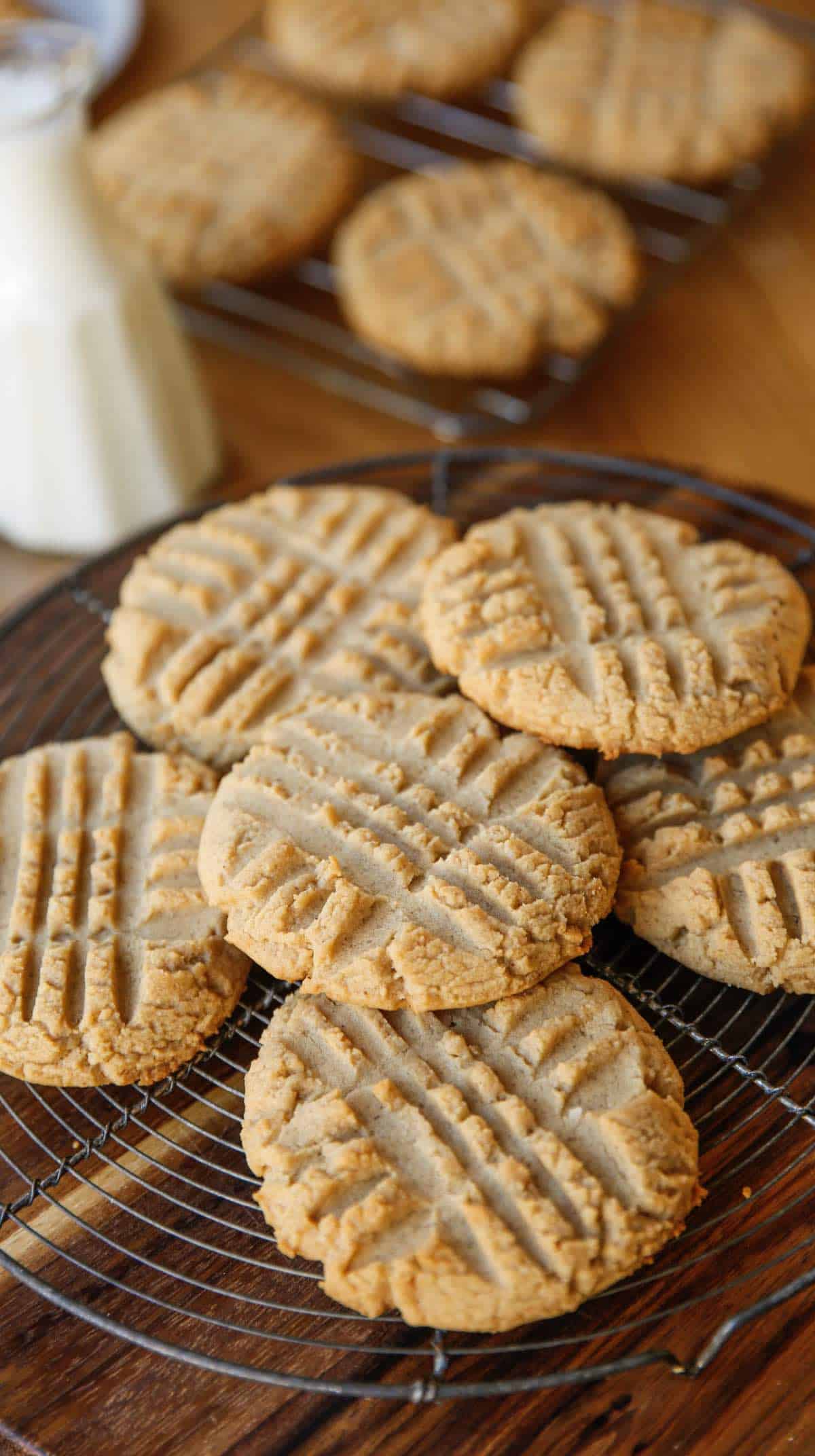 cookies cooling on a cooking rack with a pitcher of milk in the background