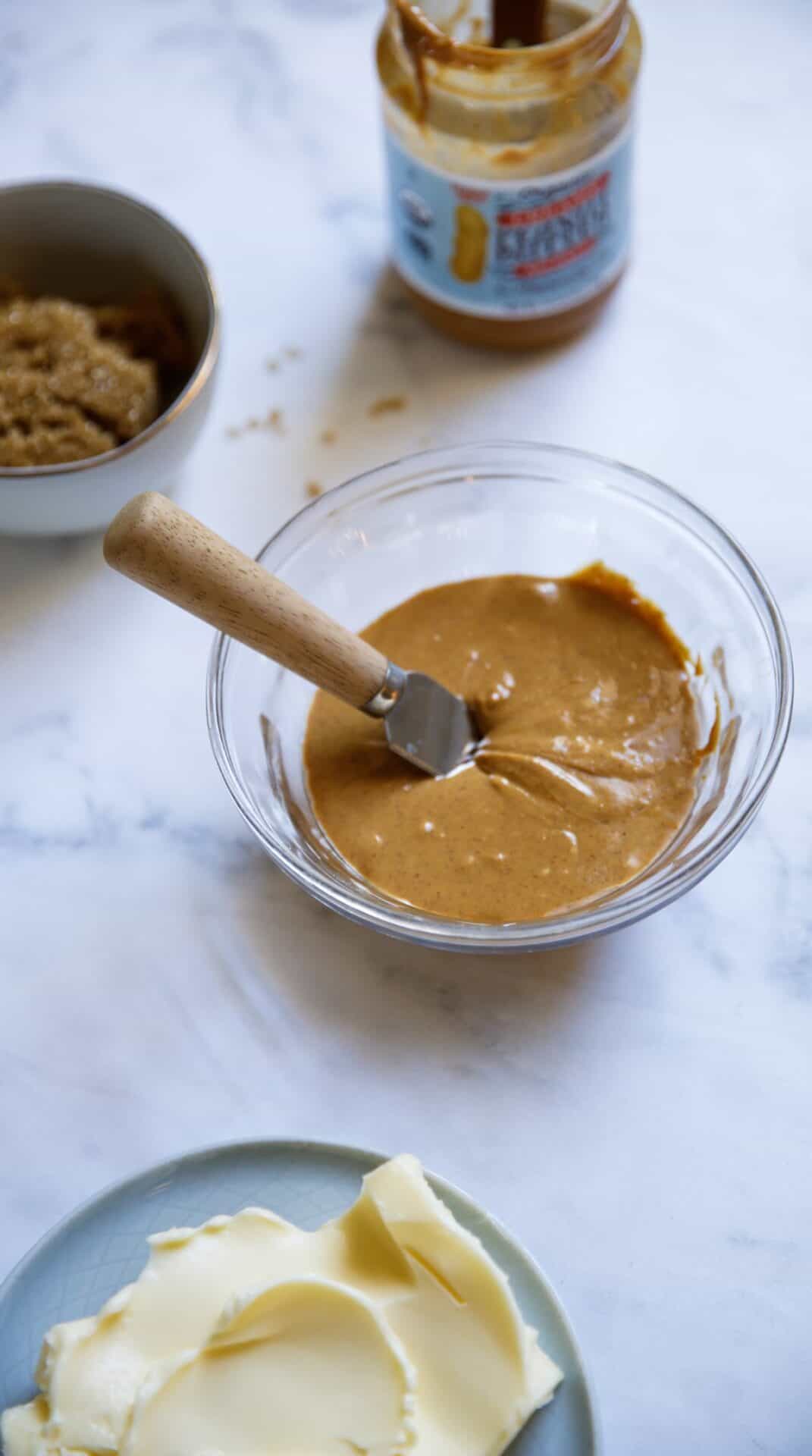 Close up of Natural Peanut Butter in a Bowl with Butter and Brown Sugar in the Background