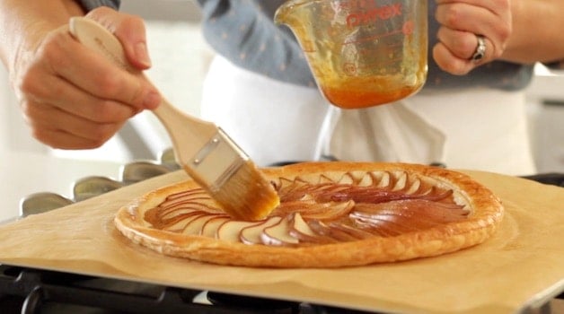 Brushing pear tart with jam after its baked