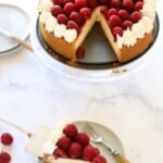 A whole raspberry cheesecake with a slice of cake on a plate with a fork