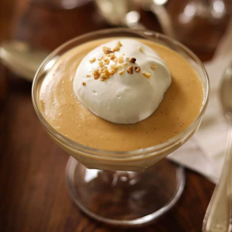 Salted Caramel Pudding in a small footed dish with whipped Cream on Top.