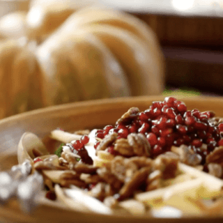 Fall Harvest Salad topped with pomegranate seeds in a large wooden bowl