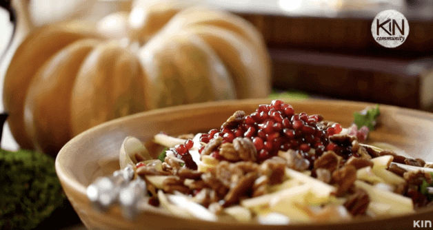 Fall Harvest Salad topped with pomegranate seeds in a large wooden bowl