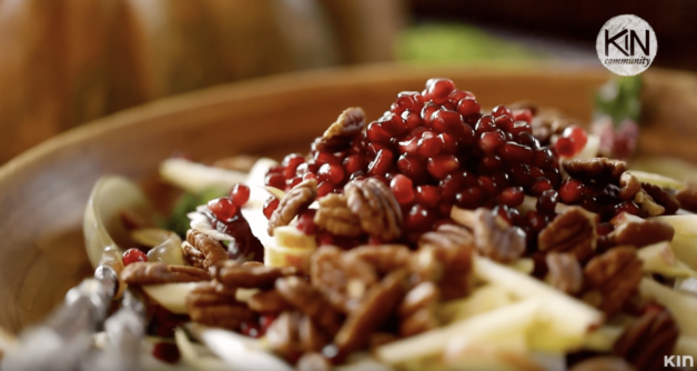 Salad with nuts, pomegranates and greens in a large wooden bowl 