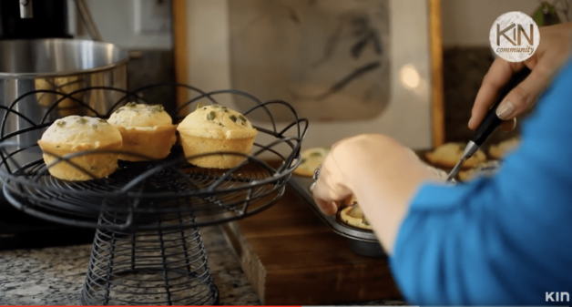 a person placing Cheesy Cornbread Muffins in a wire cake stand