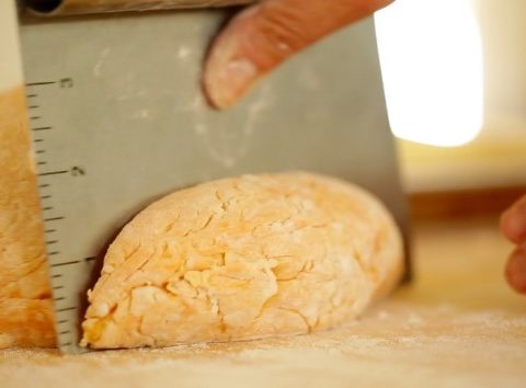 Slicing Gnocchi dough ball in half with a bench scrape
