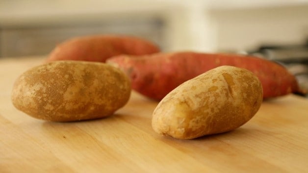 Sweet potatoes and russet potatoes on cutting board