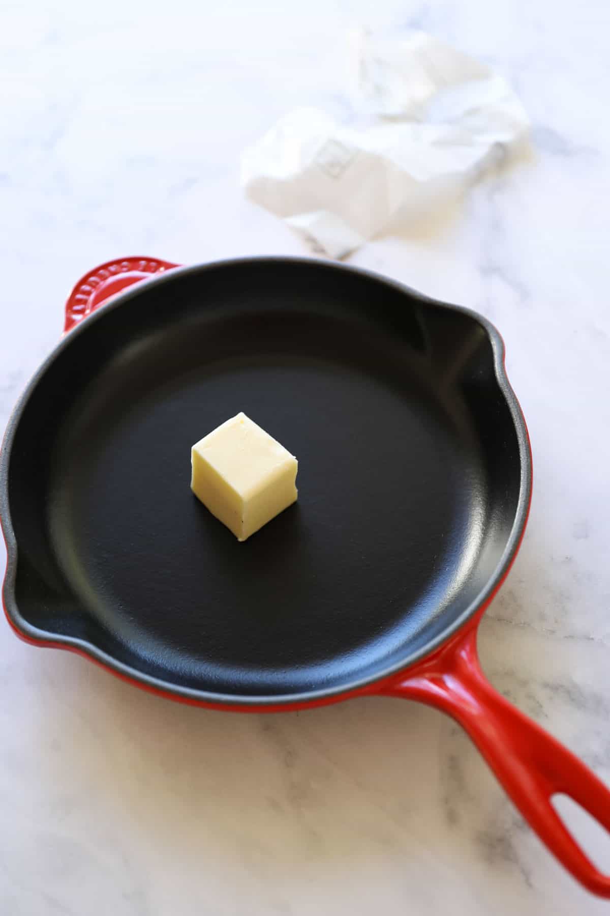 A skillet with a pat of butter inside it