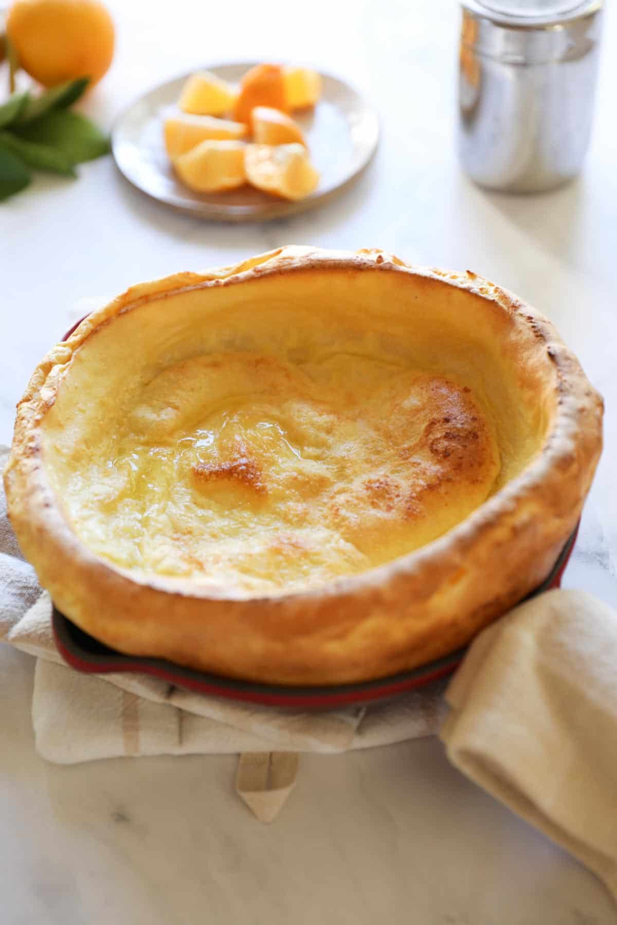 a puffy pancake in a skillet with powdered sugar