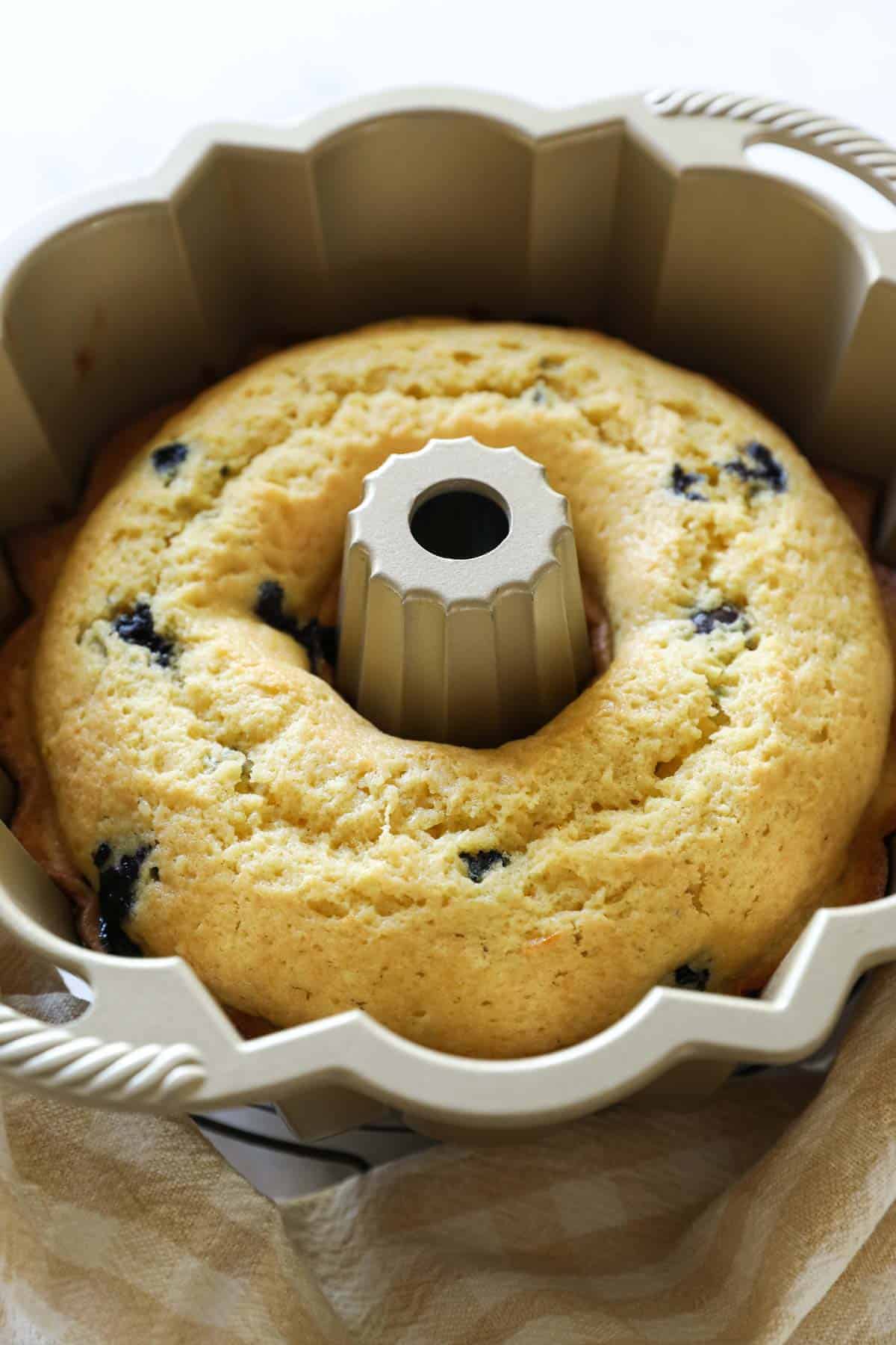 a lemon blueberry cake cooling in a bundt pan