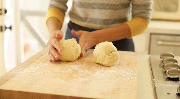 Two balls of pie dough being shaped into balls