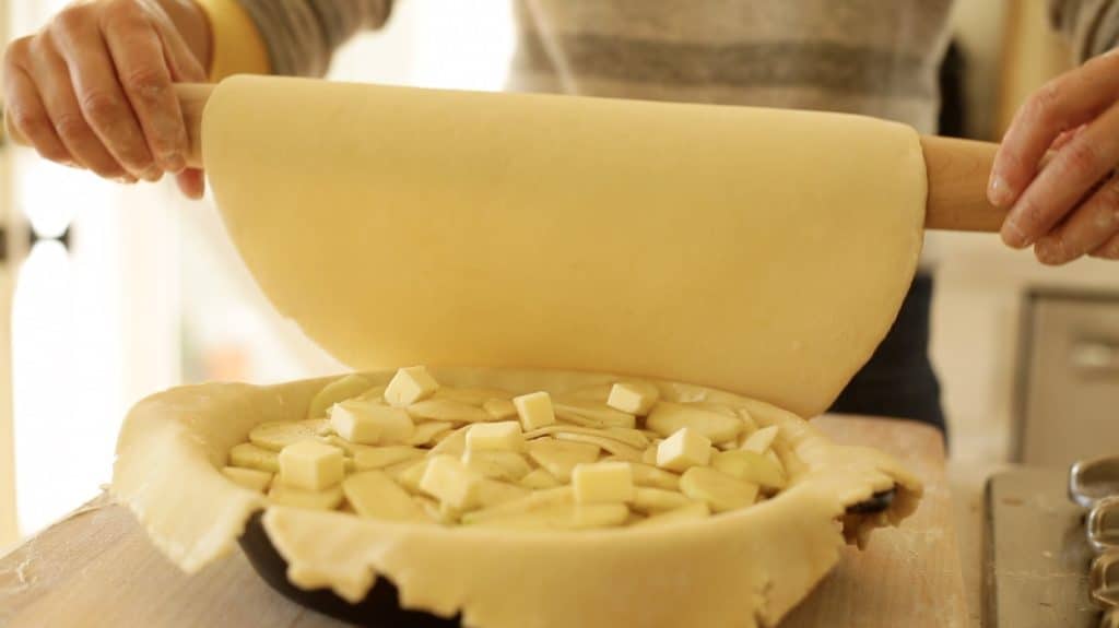 Adding the second layer of pie dough to an apple pie