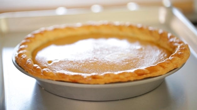 freshly baked pumpkin pie on a baking sheet cooling