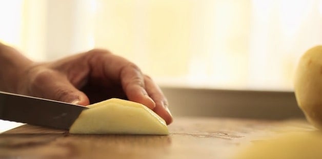 Close up detail of slicing apples into 1/8\" slices on a cutting board